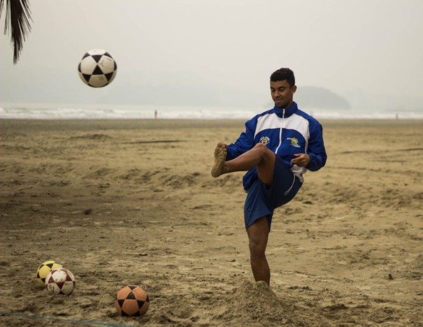 Jongen aan het voetballen op het strand